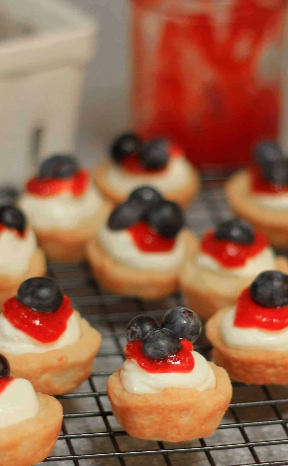 Mini Red White and Blue Lemon Cheesecake Tarts are tender homemade lemon tart shells filled with no bake lemon cheesecake filling then finished with a topping of sweet jam and berries. no bake cheesecake tarts | lemon cheesecake recipe | fruit tarts 