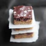 Chocolate peanut butter fudge stacked with parchment between layers