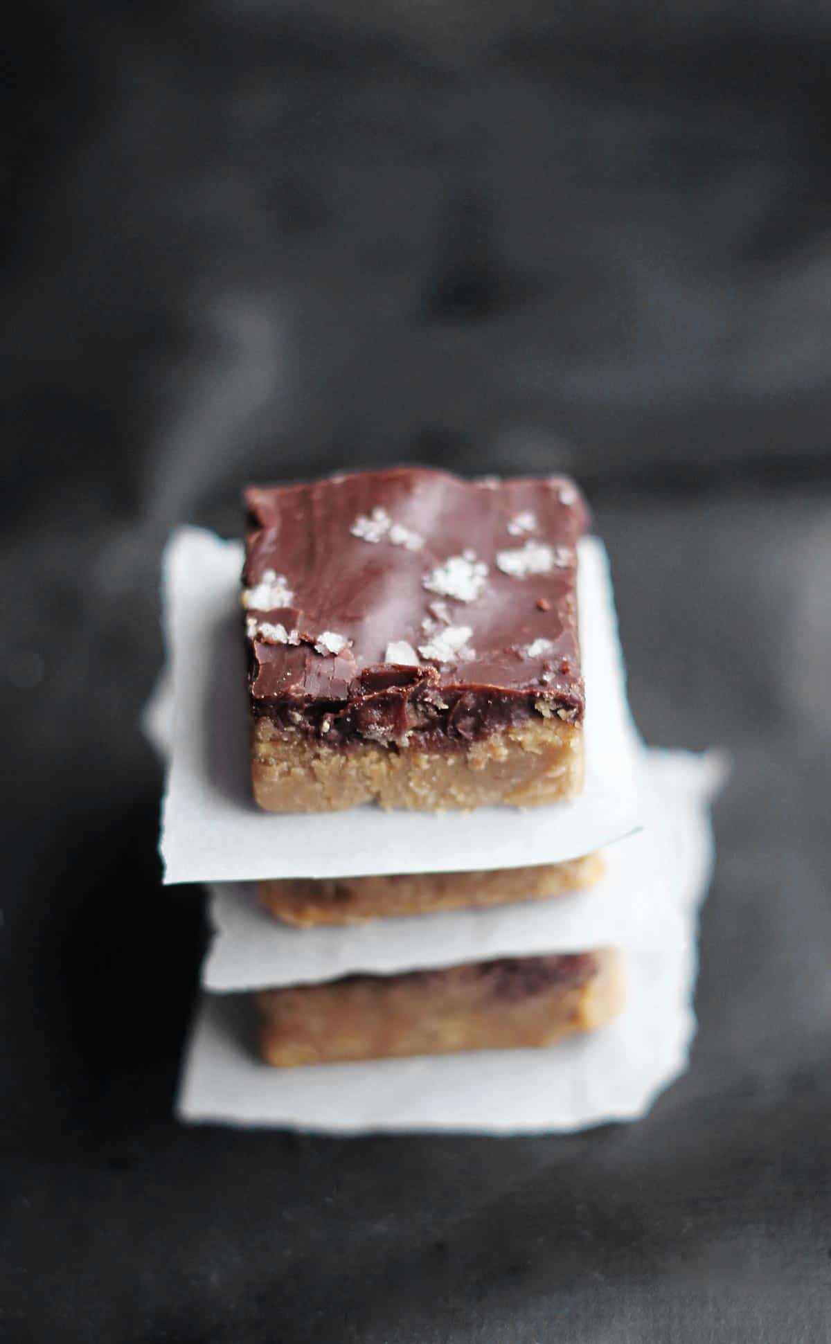 Chocolate peanut butter fudge stacked with parchment between layers