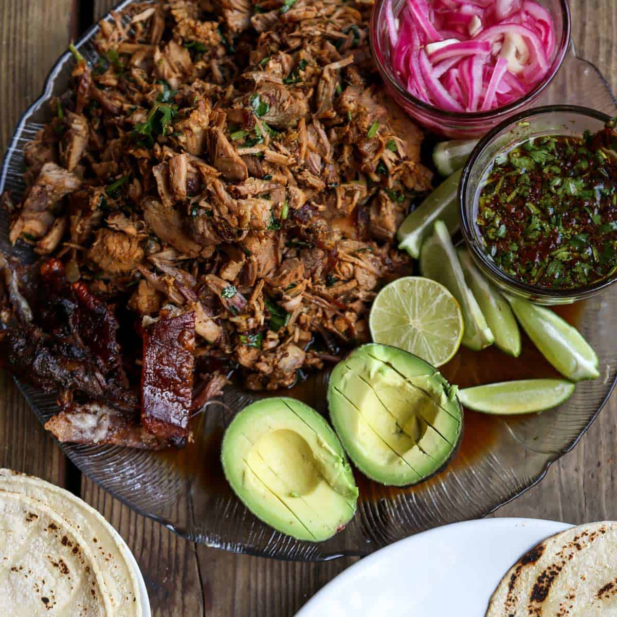 Shredded pork roast with crispy pork skin and taco fillings like avocado, lime and red onions.