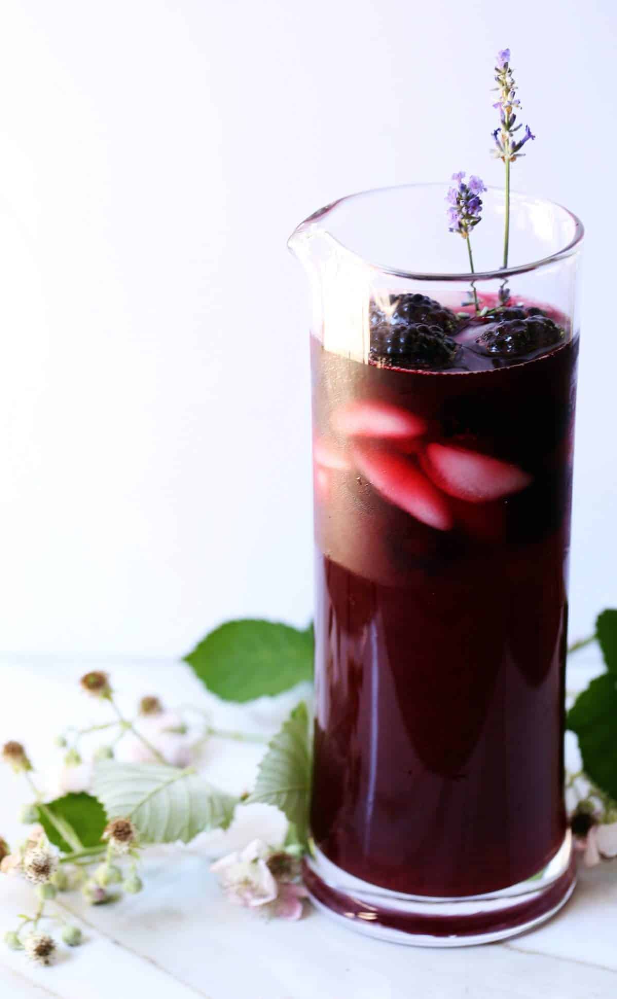 A large pitcher of naturally purple iced blackberry tea