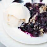 Blueberry lemon crisp made with lemon and oats served with a scoop of vanilla ice cream.