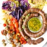Braised cabbage and kielbasa sausage sheet pan meal with bursted cherry tomatoes.