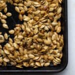 Roasted pumpkin seeds on a sheet pan.