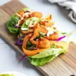 Crispy shrimp in a crisp lettuce wrap with carrot ribbons and crunchy toppings.