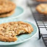 Trail mix cookie with visible chopped nuts and oats on a plate with a bite out of it.