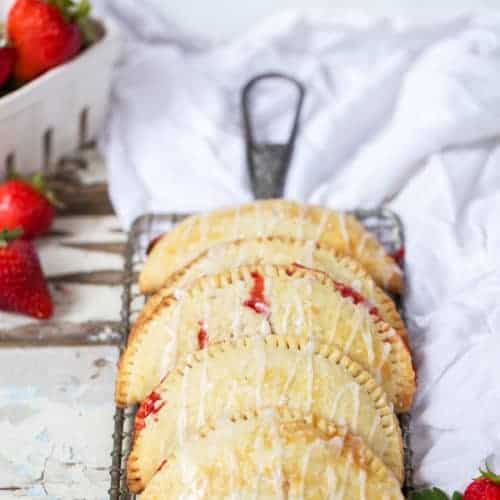 An easy two ingredient filling and a sturdy but flaky crust make these portable Strawberry Lemonade Hand Pies a hit at all your summer occasions! #strawberries #strawberrylemonade #handpies #strawberrypie How to Make Hand Pies | How to Freeze Hand Pies | Strawberry Hand Pies | Lemon Hand Pies | Lemon Pastry from ONEarmedMAMA.com