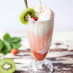 Fresh strawberry ice cream float in a float glass garnished with fresh kiwi and strawberries.