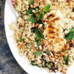 Quinoa salad recipe with chicken, herbs, fresh blueberries, kale and almonds served on a large white platter.