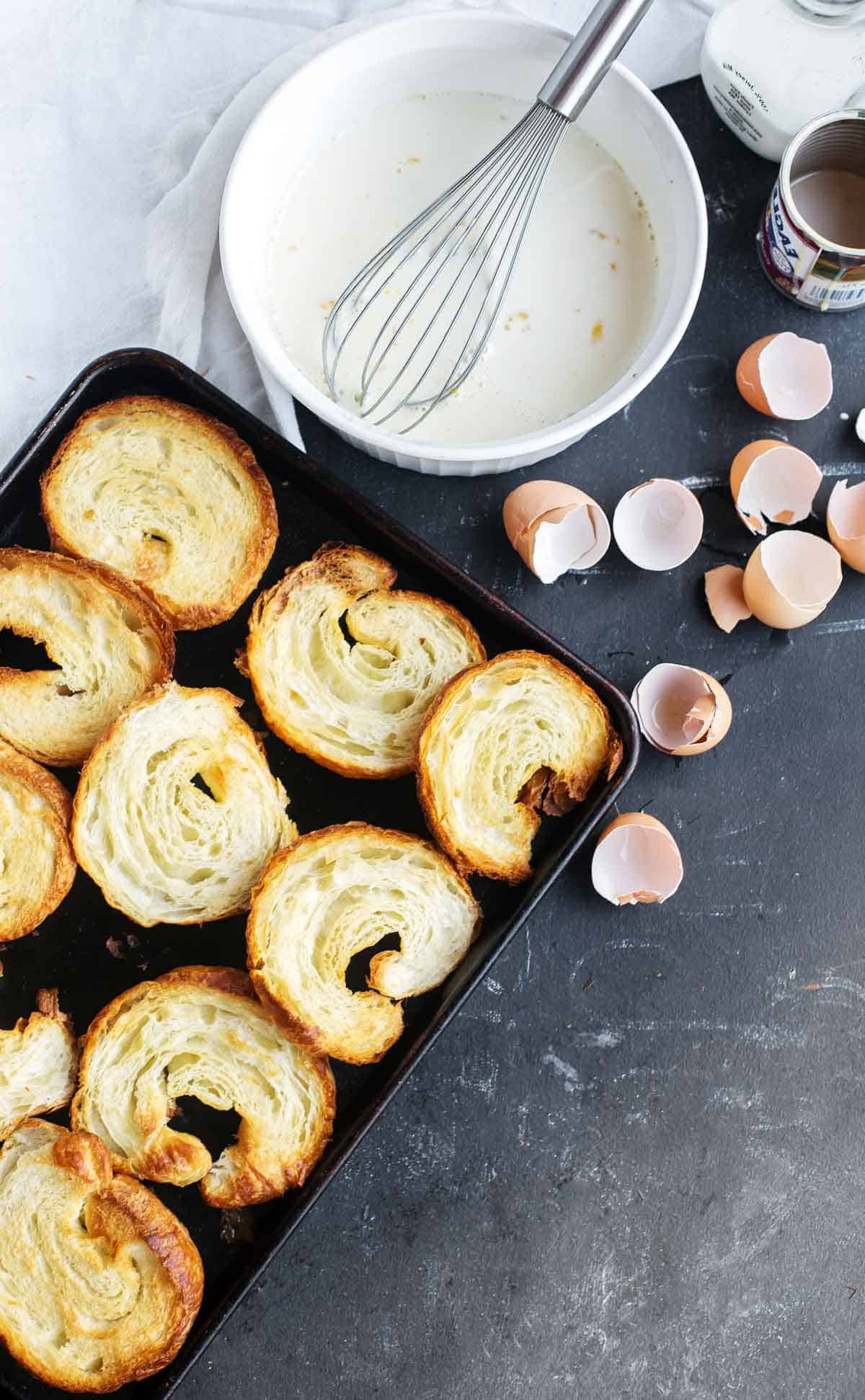 Ingredients to make french toast casserole with croissants in a cinnamon custard.