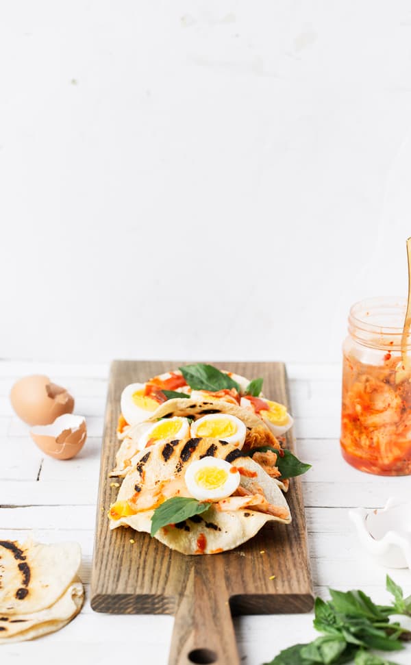 A quick, fueling breakfast Kimchi Egg Tacos combine perfectly cooked hard-boiled eggs with fresh basil and Korean kimchi and gochujang sauce | with gochujang corn tortillas | breakfast ideas | kimchi eggs recipes