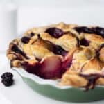 Blackberry and pear pie in a green pie pan with a slice missing.