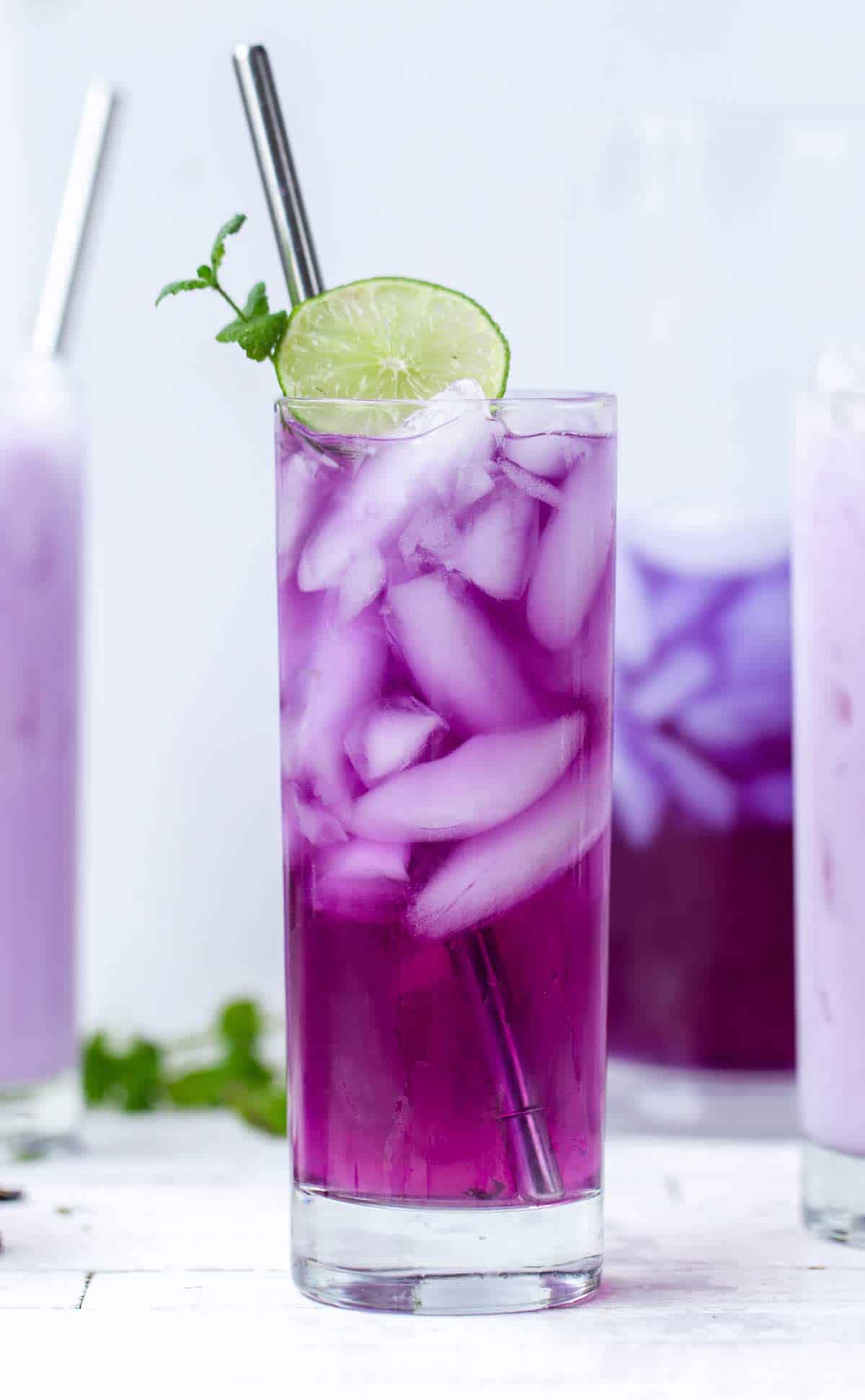 Close up of magenta tea with lime and mint and a creamy option in the background.