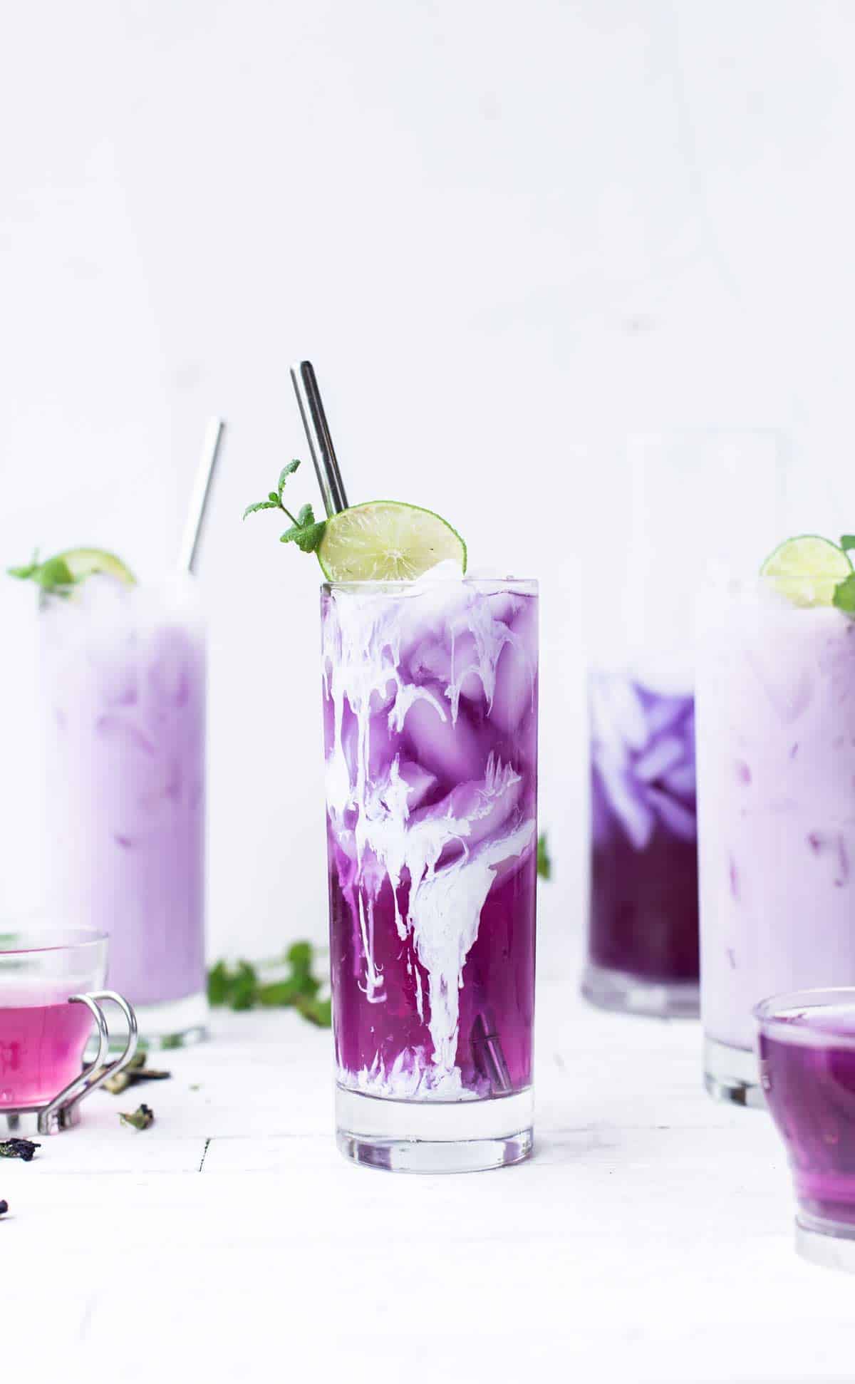 Purple iced tea with cream and garnished with lime and mint.