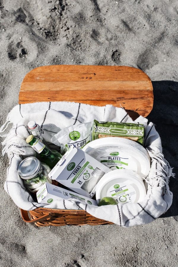 vintage wood picnic basket with compostable products for earth day at the beach