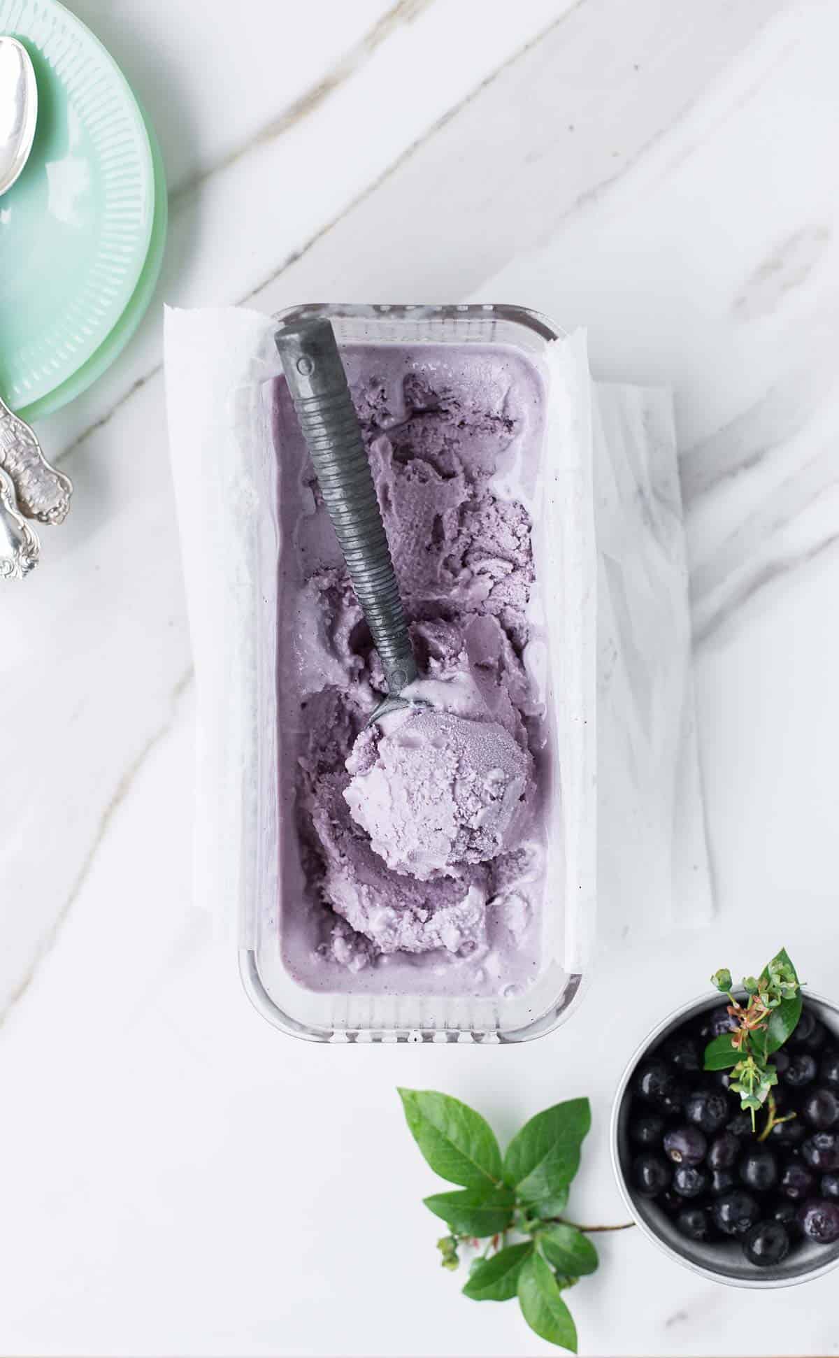 Top down view of blueberry gelato with jadeite dishes and silver spoons on the side.