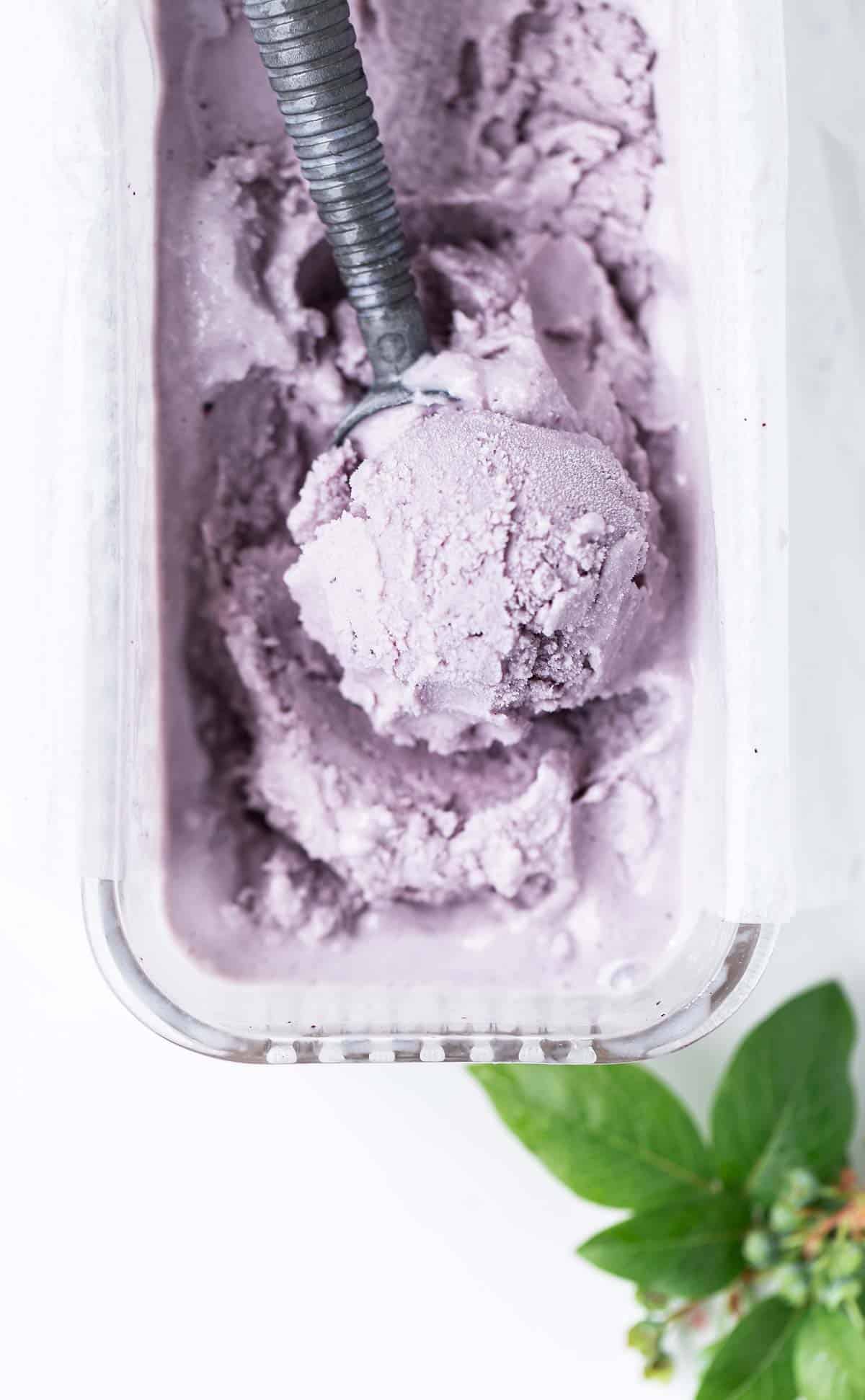 Scoop of pastel purple blueberry gelato shown in a vintage glass dish lined with parchment.