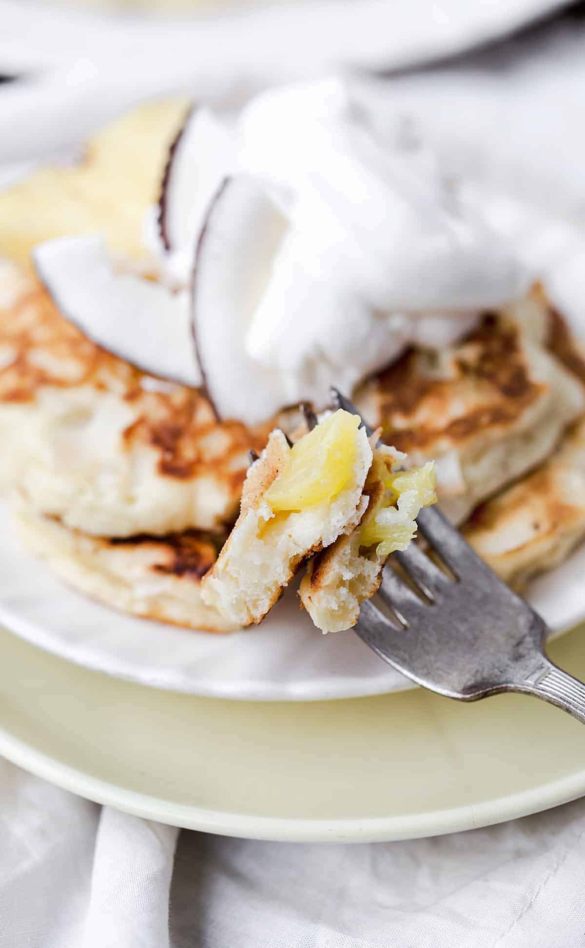 fork shot of juicy pineapple surrounded by fluffy pancake