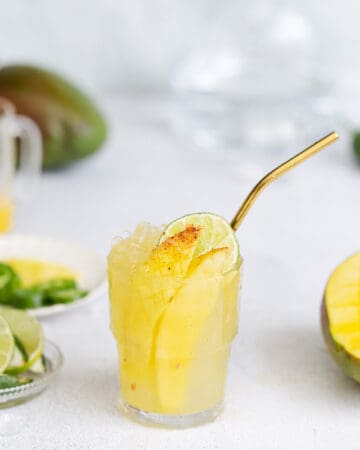vibrant mango cocktail with a spicy mango spear in a cold glass