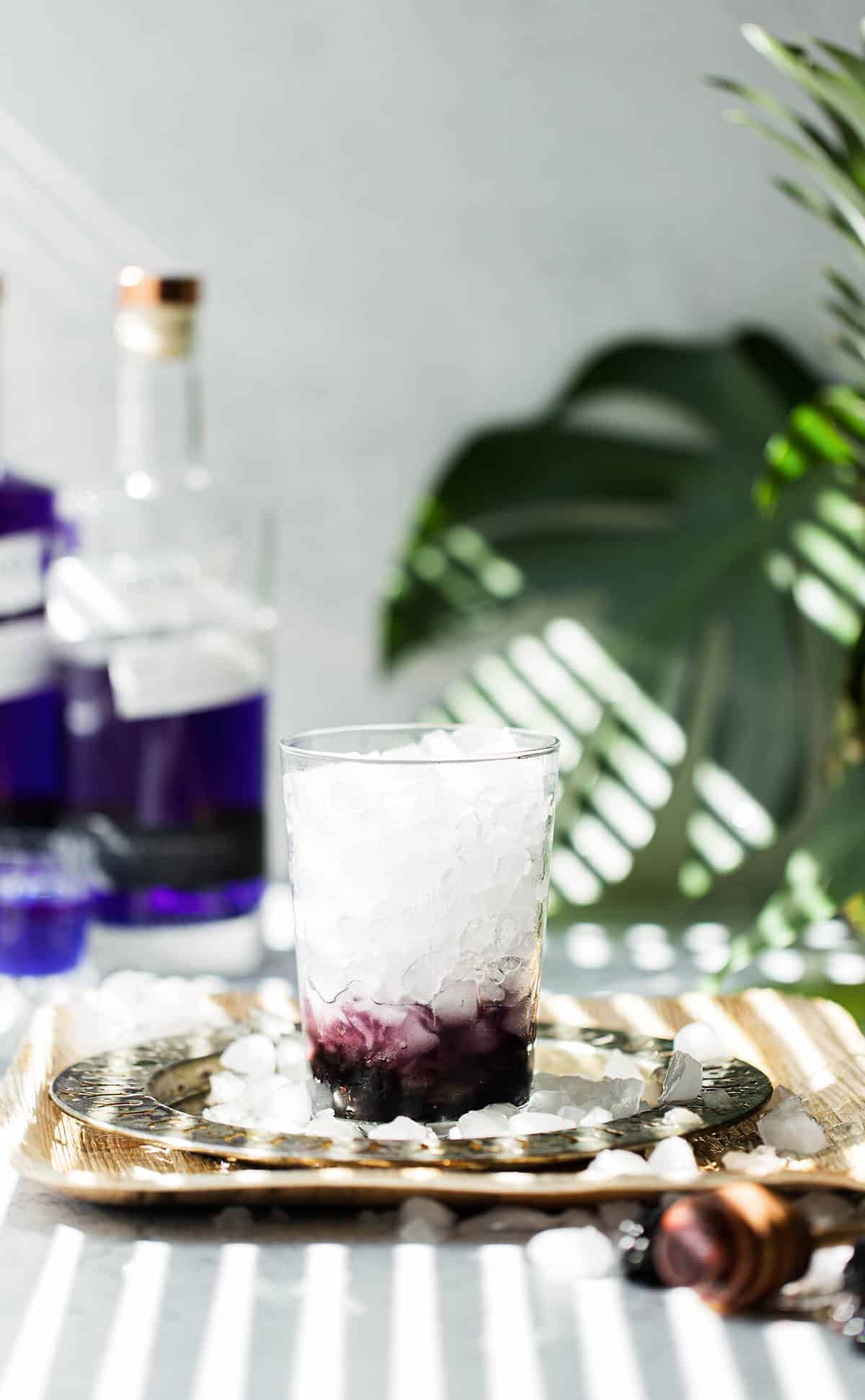 Muddled blackberries and honey in a glass with crushed ice