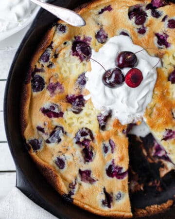 Top down view of cherry clafouti in a casti iron skillet topped with cherries.