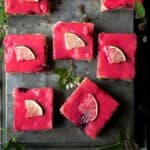 Blackberry blondie squares with bright pink blackberry glaze and a thin slice of lime on each square.