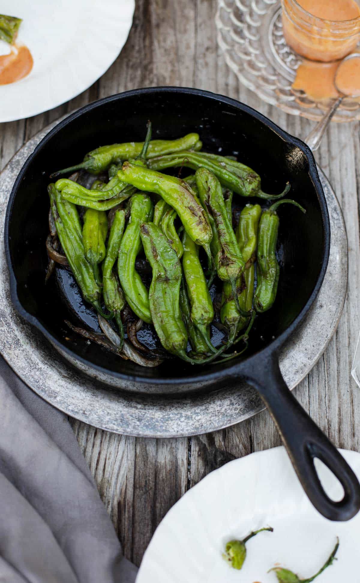 Blistered Shishito Peppers with dipping sauce is a delicious easy appetizer recipe that can be cooked in a cast iron on the stove, grilled on the bbq, baked in the oven and even made in the air fryer. shishito peppers | shishito peppers recipe | japanese peppers