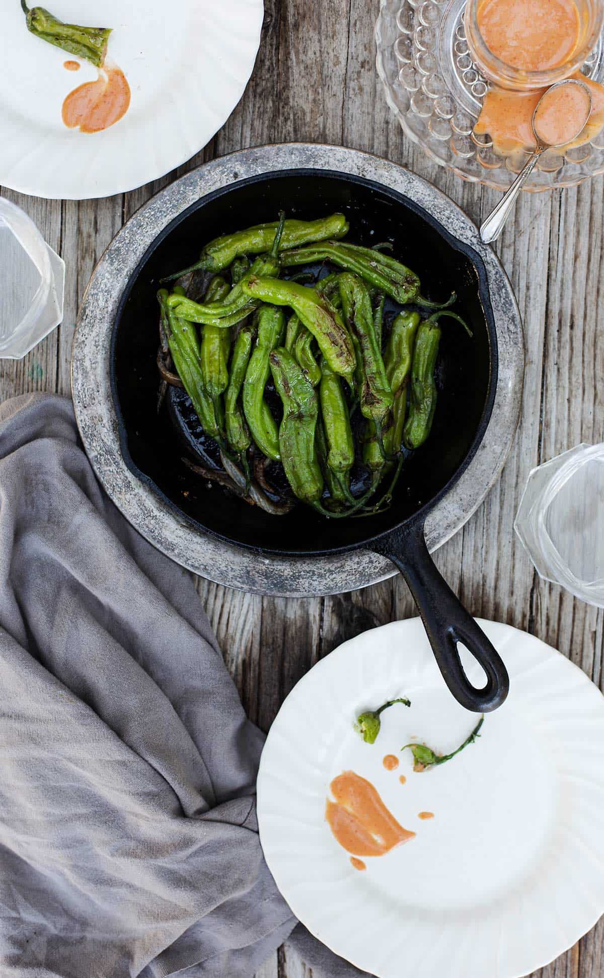 Blistered Shishito Peppers with dipping sauce is a delicious easy appetizer recipe that can be cooked in a cast iron on the stove, grilled on the bbq, baked in the oven and even made in the air fryer. shishito peppers | shishito peppers recipe | japanese peppers 