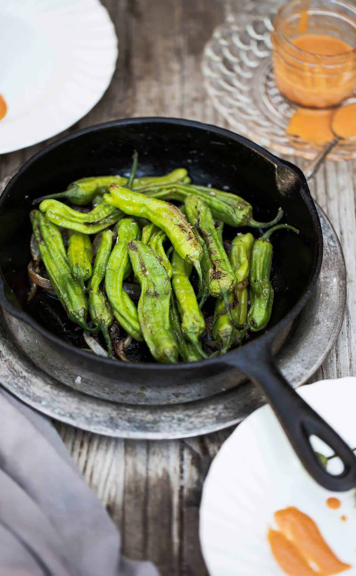 Blistered Shishito Peppers with dipping sauce is a delicious easy appetizer recipe that can be cooked in a cast iron on the stove, grilled on the bbq, baked in the oven and even made in the air fryer. shishito peppers | shishito peppers recipe | japanese peppers 