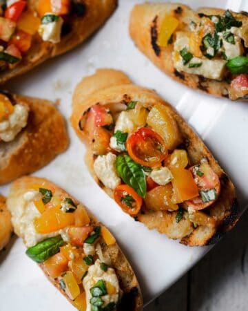 Tomato Bruschetta with Cheese is a delicious Italian antipasto recipe with cherry tomatoes, heirloom tomatoes, squeaky cheese, garlic and basil. bruschetta recipe | tomato bruschetta | easy bruschetta tomate