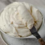Homemade cream cheese icing in a bowl and on an icing spatula.