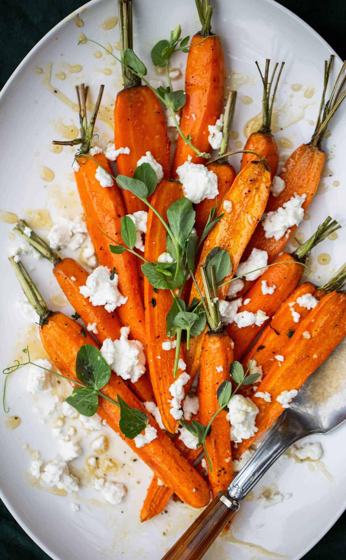 Roasted carrots with honey on a white platter with a dark background