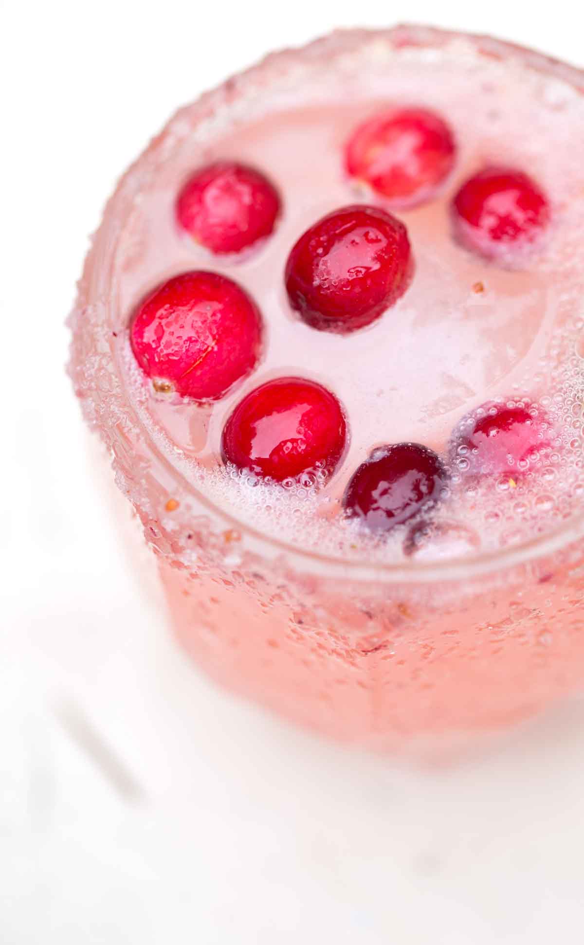 Fizzy pink cocktail in a glass with fresh cranberries.