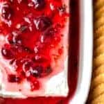 Cranberry jalapeno cream cheese dip close up in a white dish with buttery crackers.