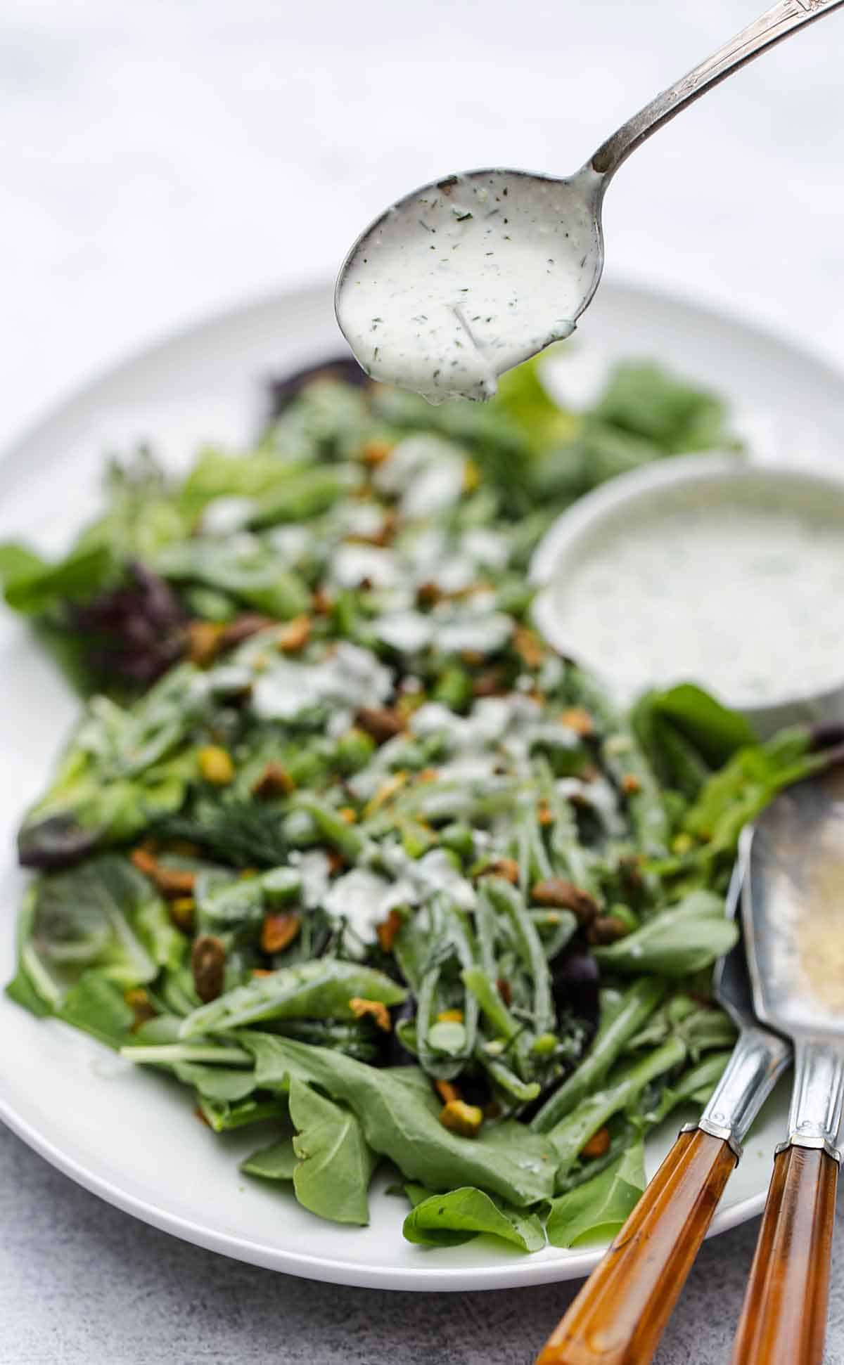 Homemade ranch being drizzled on a salad.